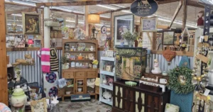 Antique mall booth filled with vintage inventory including glassware, decor, and collectibles displayed on shelves