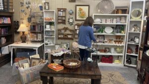 Vendor restocking vintage items in an antique mall booth to keep shelves full and displays fresh